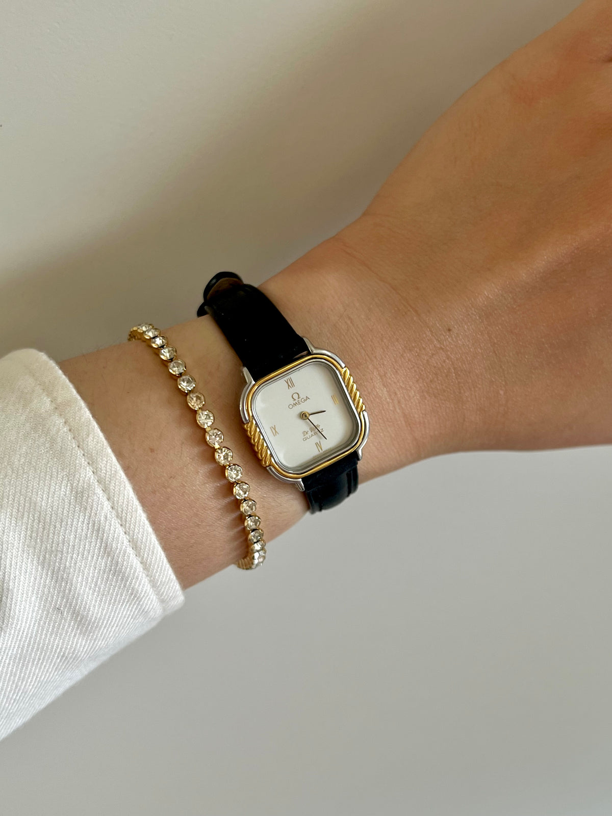 Angled view of the Omega De Ville cushion case and two twisted gold bezel columns.