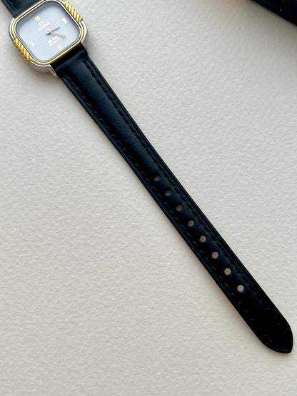 Detail of the Omega De Ville white dial with gilt Roman hour markers and slim hands.