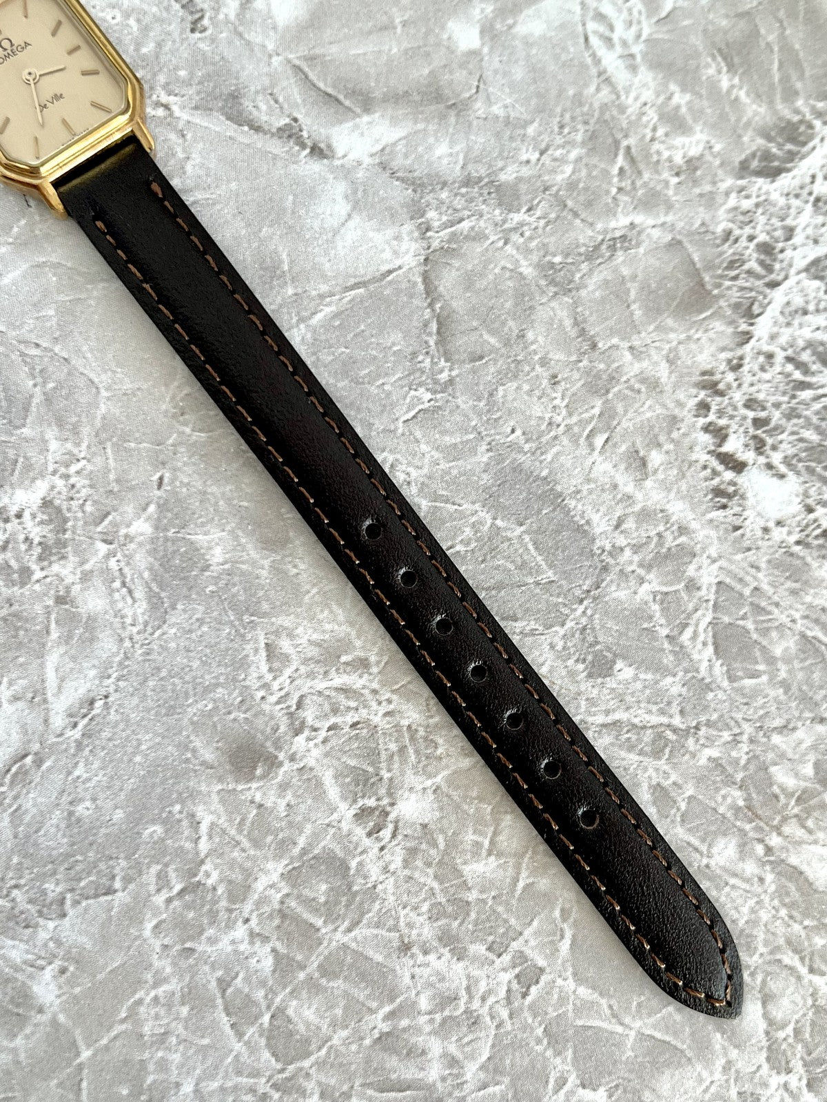 Adjustable dark stitched strap and fit holes on Omega De Ville rectangular watch