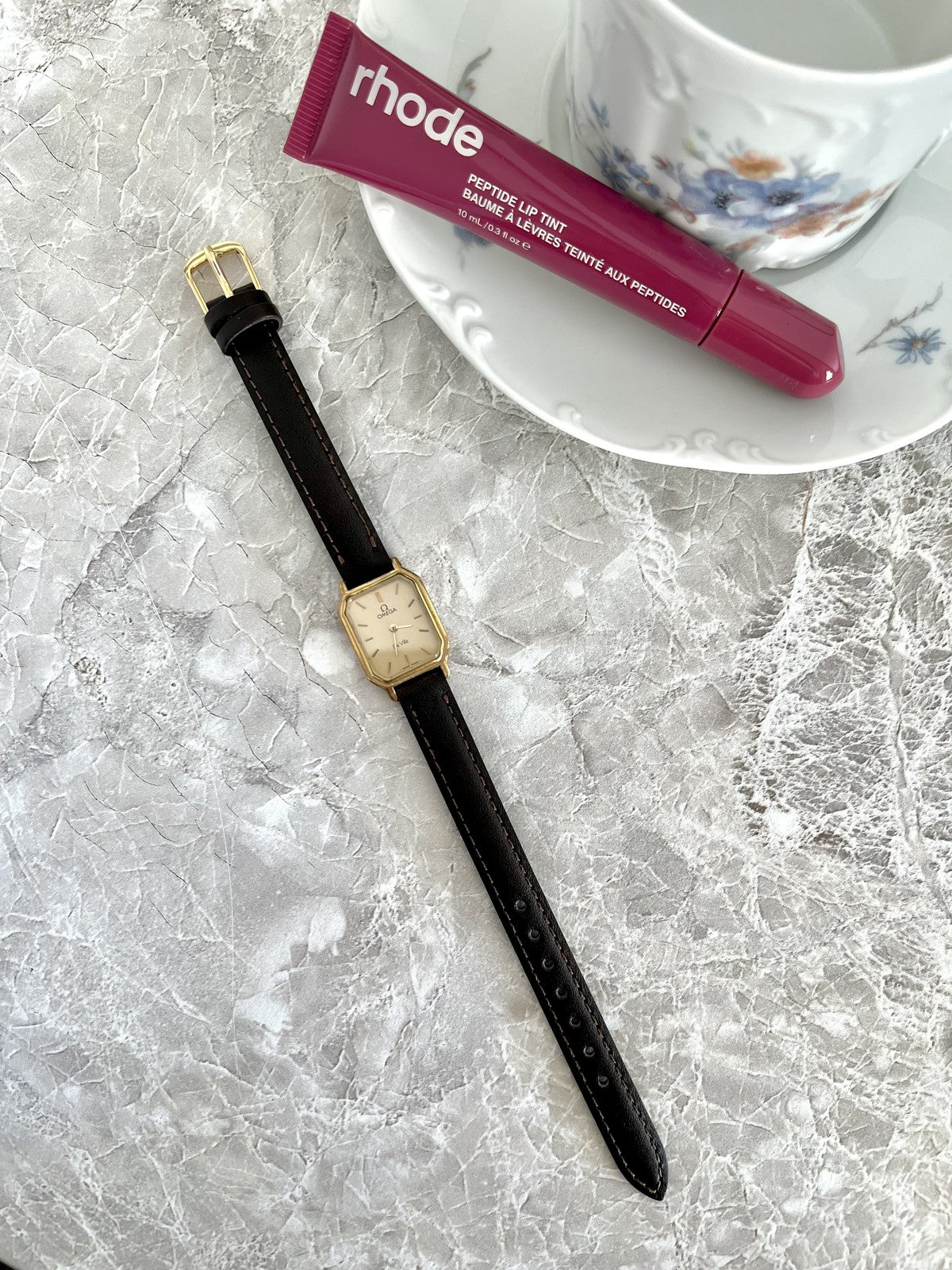 Omega De Ville quartz women's watch with champagne dial and dark strap, full-length editorial view