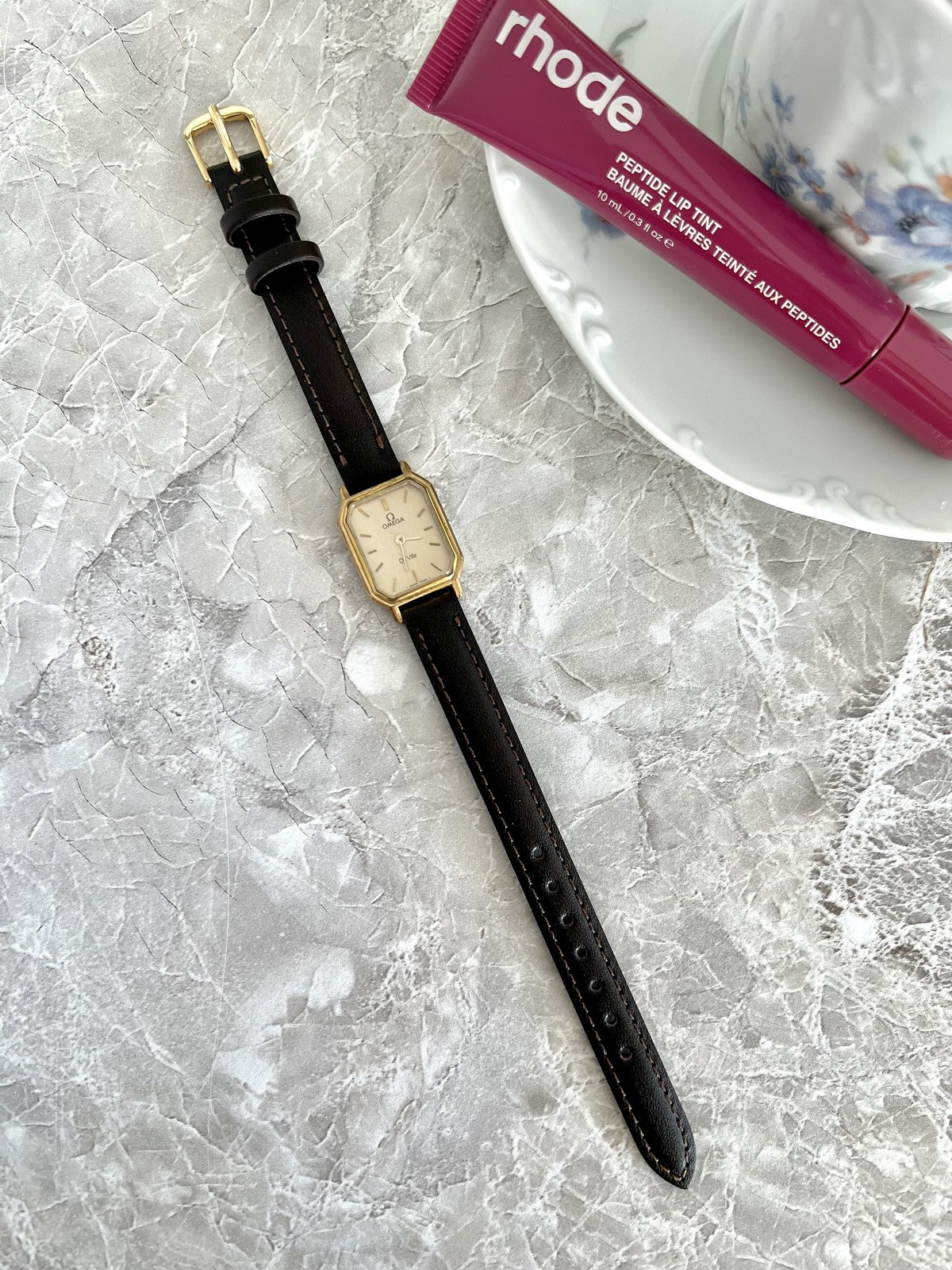 Full-length Omega De Ville champagne-dial rectangular watch with dark stitched strap and gold-tone buckle