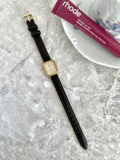 Full-length Omega De Ville champagne-dial rectangular watch with dark stitched strap and gold-tone buckle