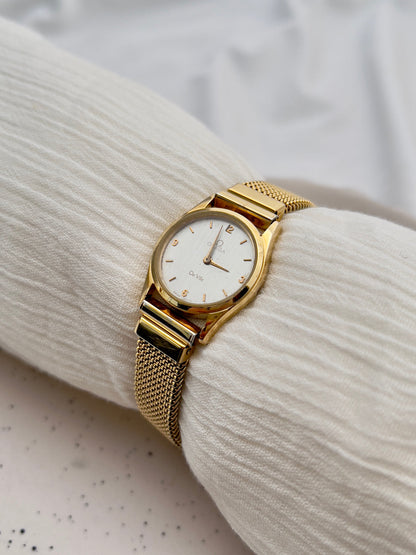 Omega De Ville ladies quartz watch with gold-tone case and woven mesh bracelet.
