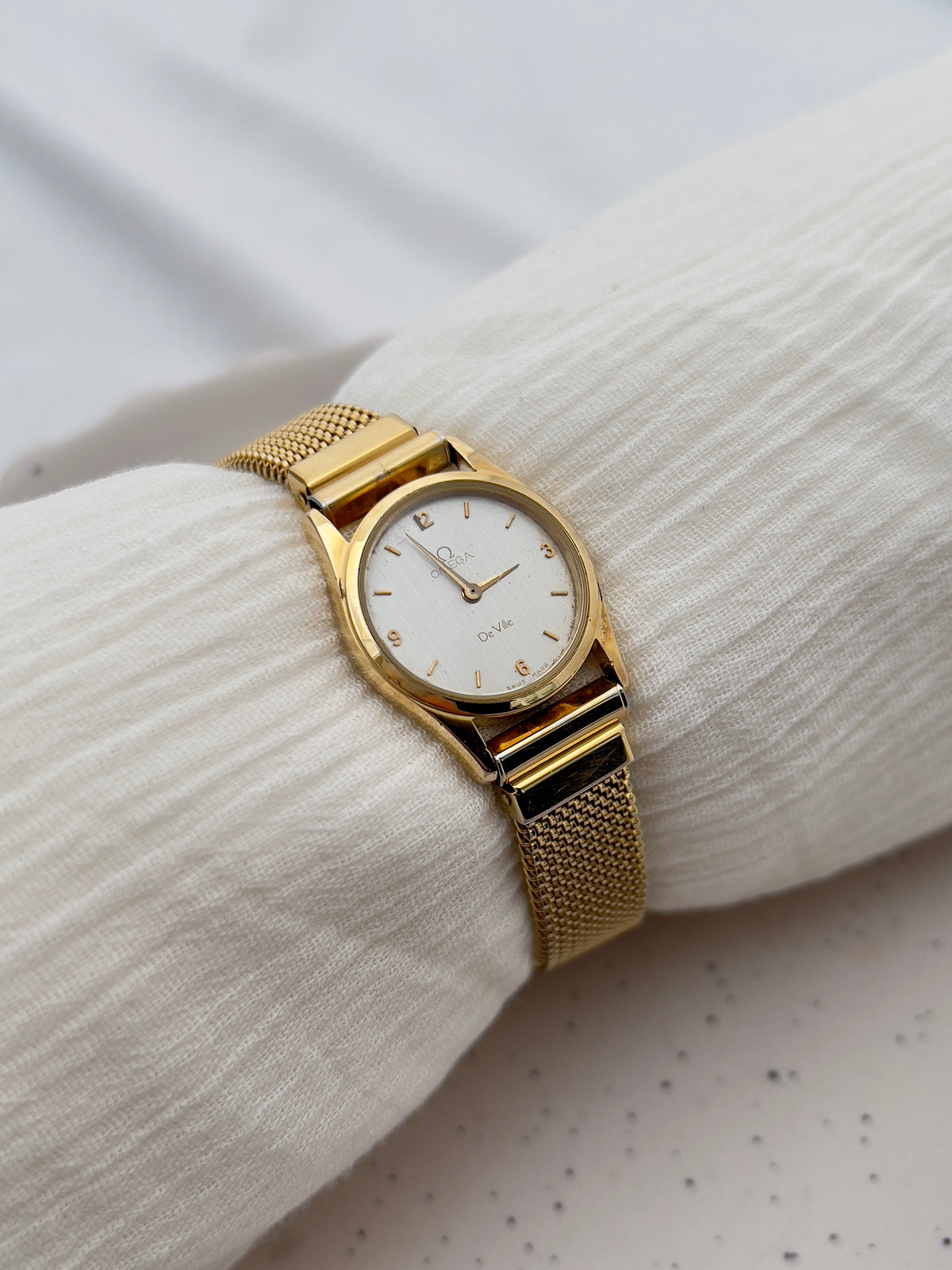 Omega De Ville watch with silver dial, subtle gold numerals and delicate hands.