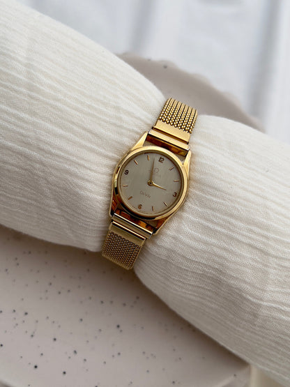 Gold-tone Omega De Ville watch with integrated elastic mesh bracelet.