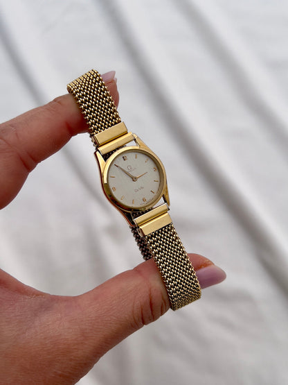 Omega De Ville gold mesh bracelet watch with understated silver dial.