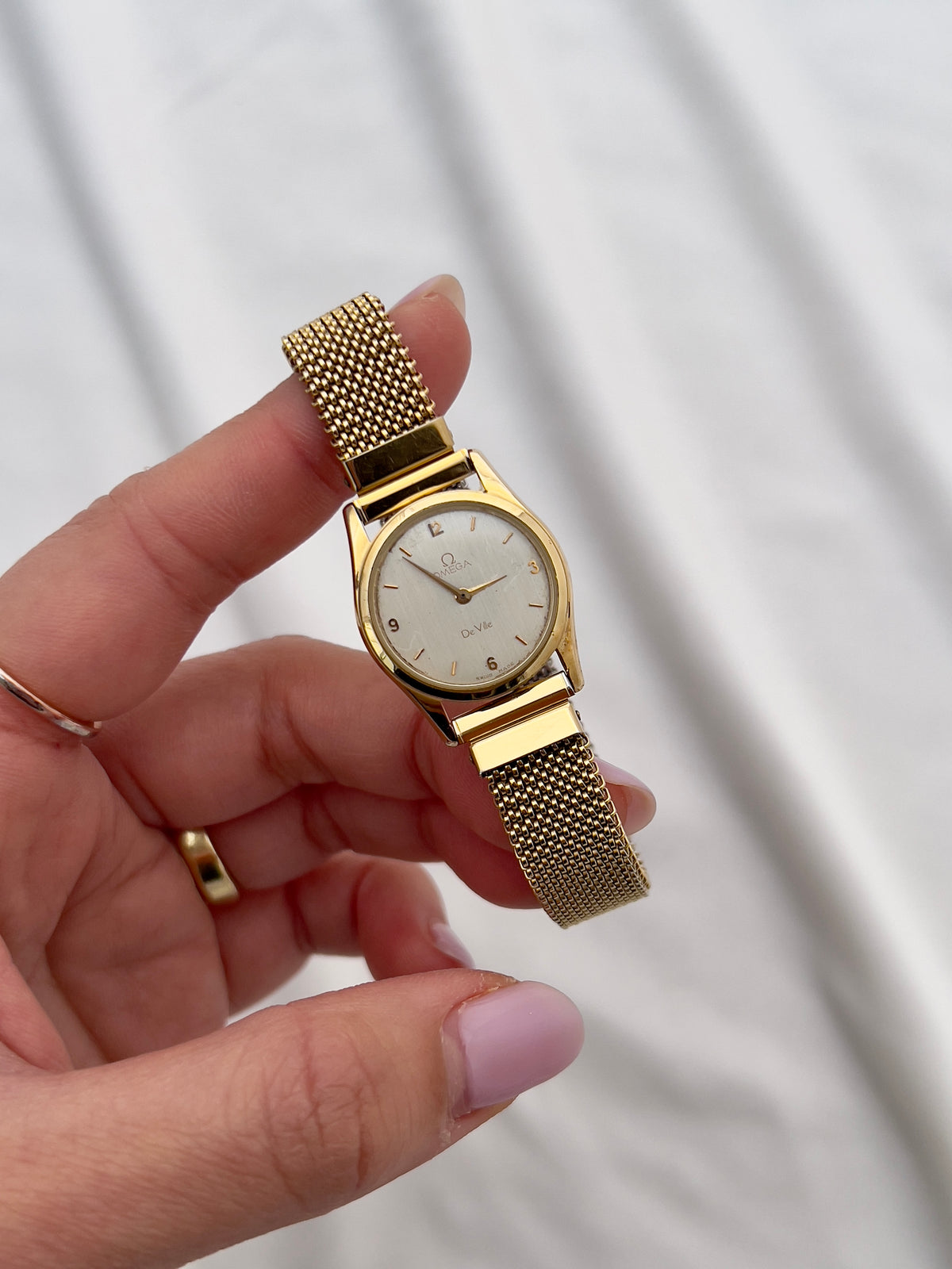 Omega De Ville vintage quartz watch with integrated gold-tone elastic bracelet.