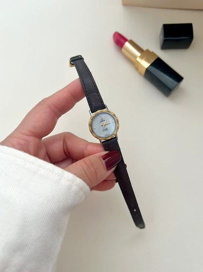 Angled view of the Omega De Ville gold laurel bezel and shimmering mother-of-pearl dial.