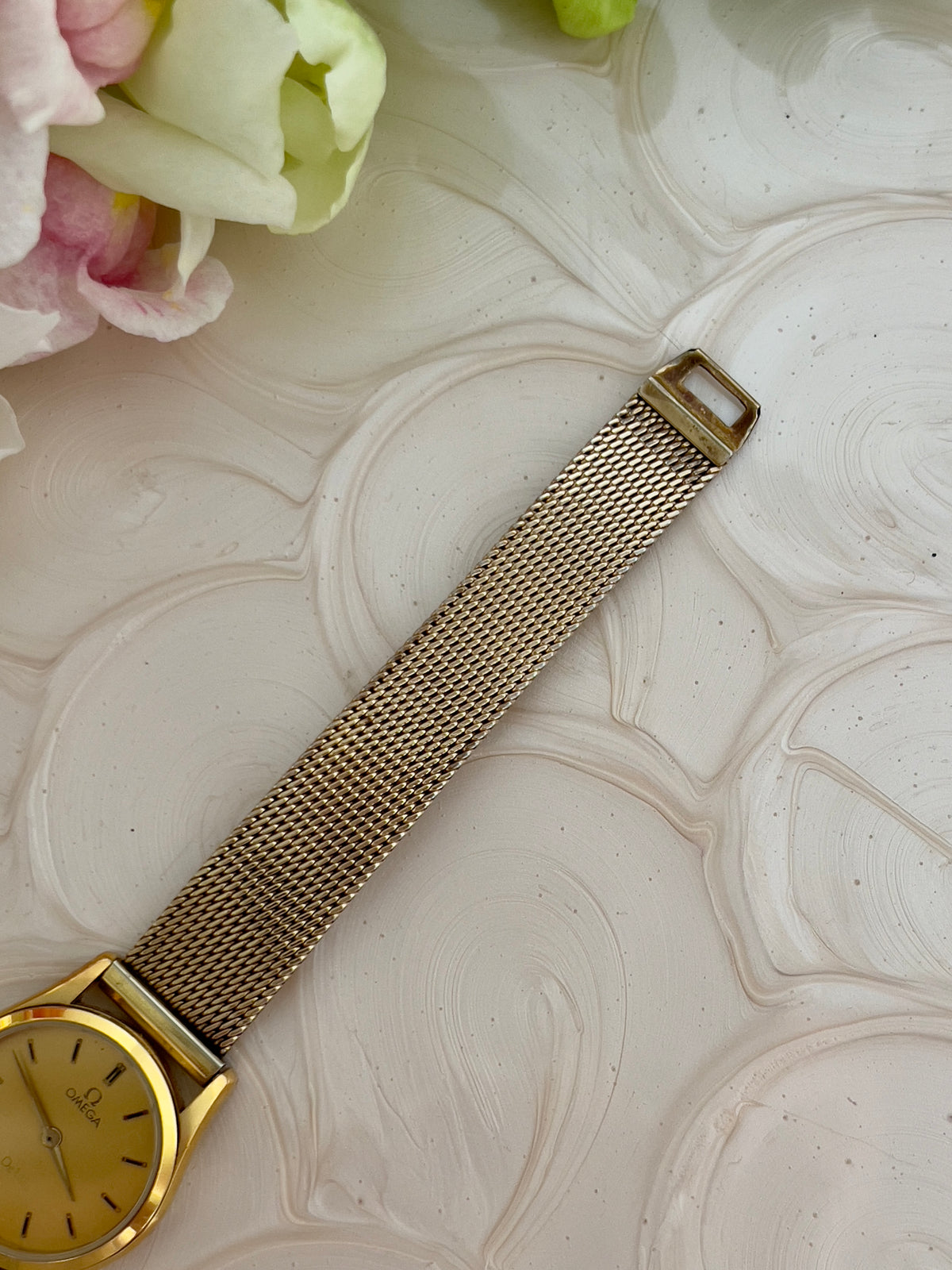 Angled view of the Omega De Ville gold watch with golden satin dial.