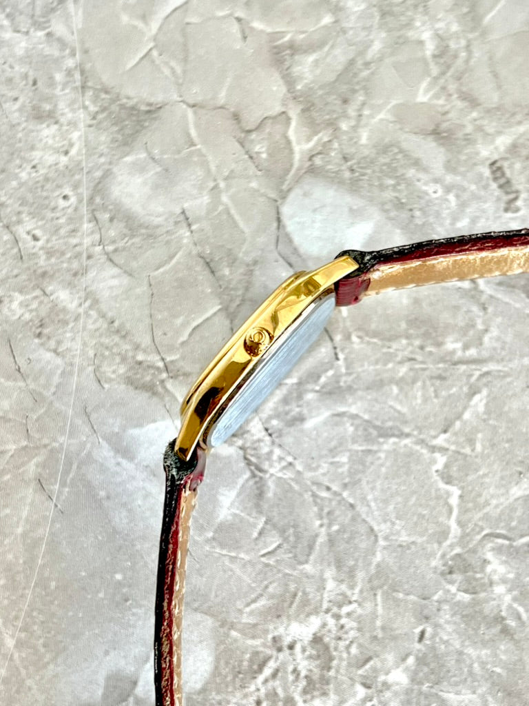 Side profile of the slim gold-tone Omega De Ville oval watch case and crown
