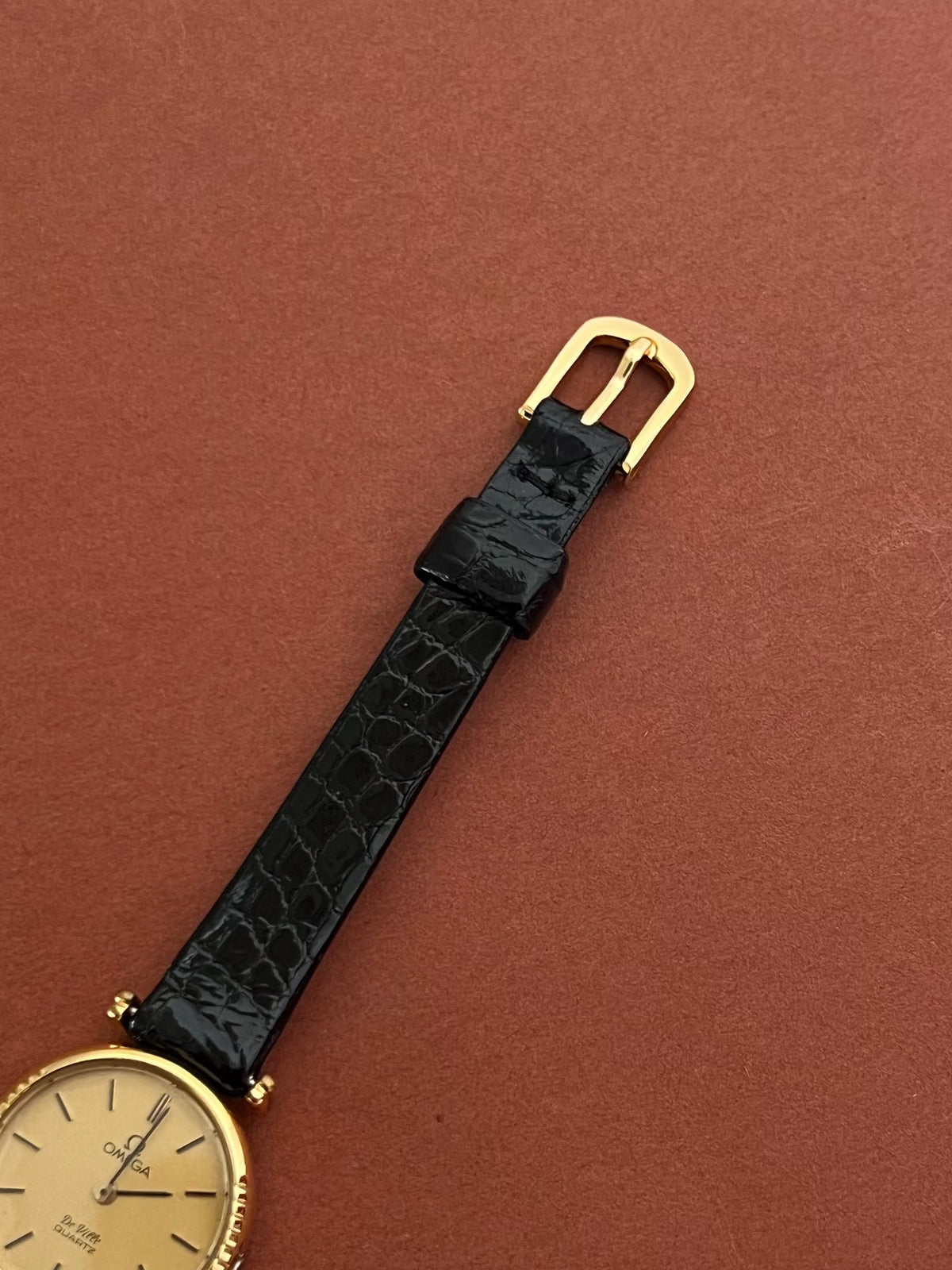 Angled view of the Omega De Ville round case and black leather strap.