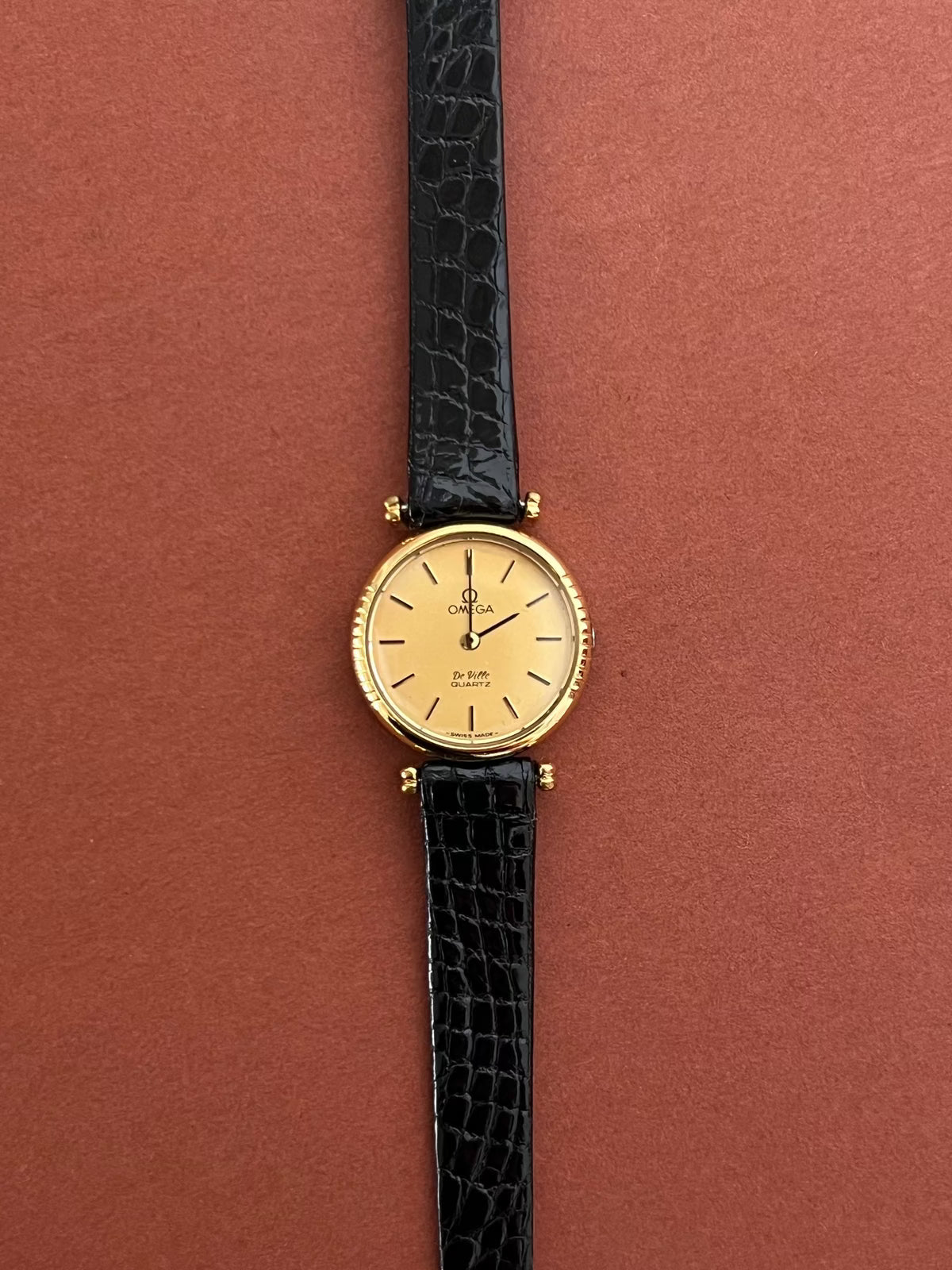Detail of the black leather strap and gold-tone buckle on the Omega De Ville.