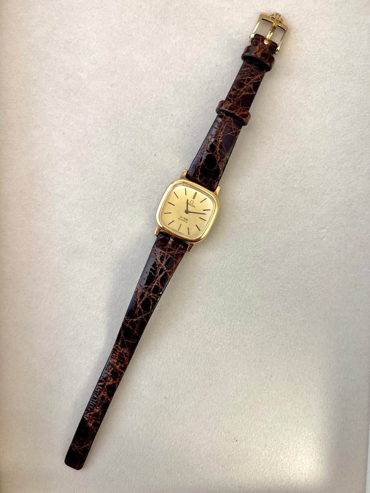 Close-up of the Omega De Ville dial with black baton markers and Omega emblem.