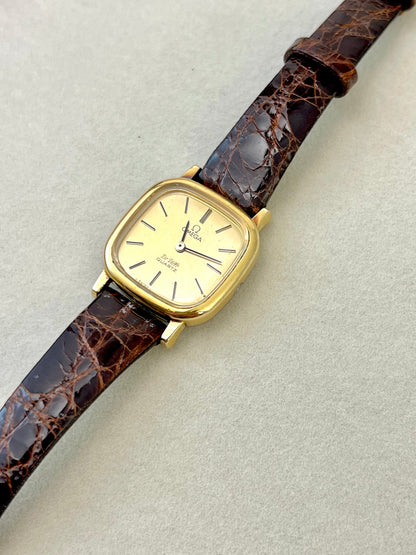 Wrist view of the Omega De Ville gold square watch with leather strap.