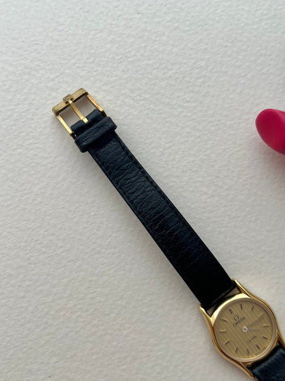 Omega women's gold watch with a textured dial and signed crown.