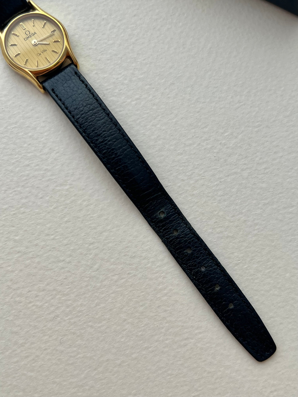 Vintage Omega De Ville watch with gold case and baton hands.