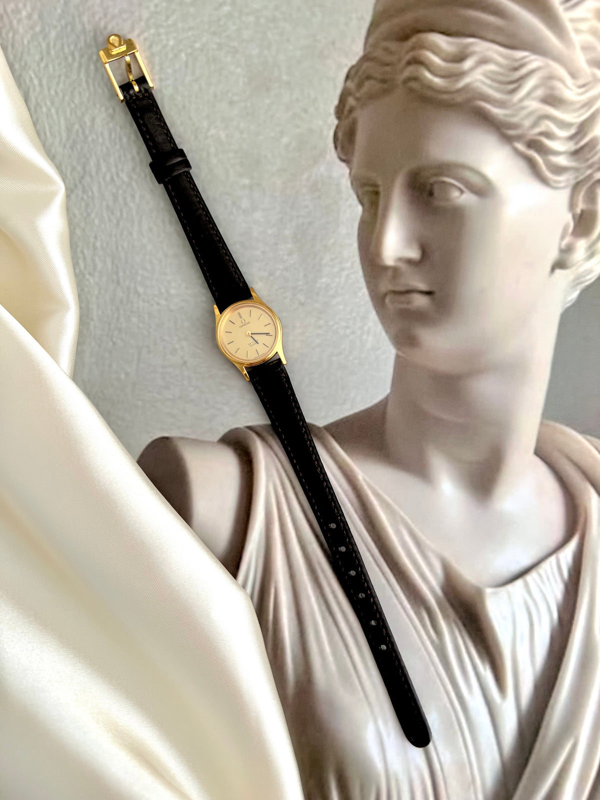 Angled view of the Omega De Ville gold-tone watch with brown leather strap.