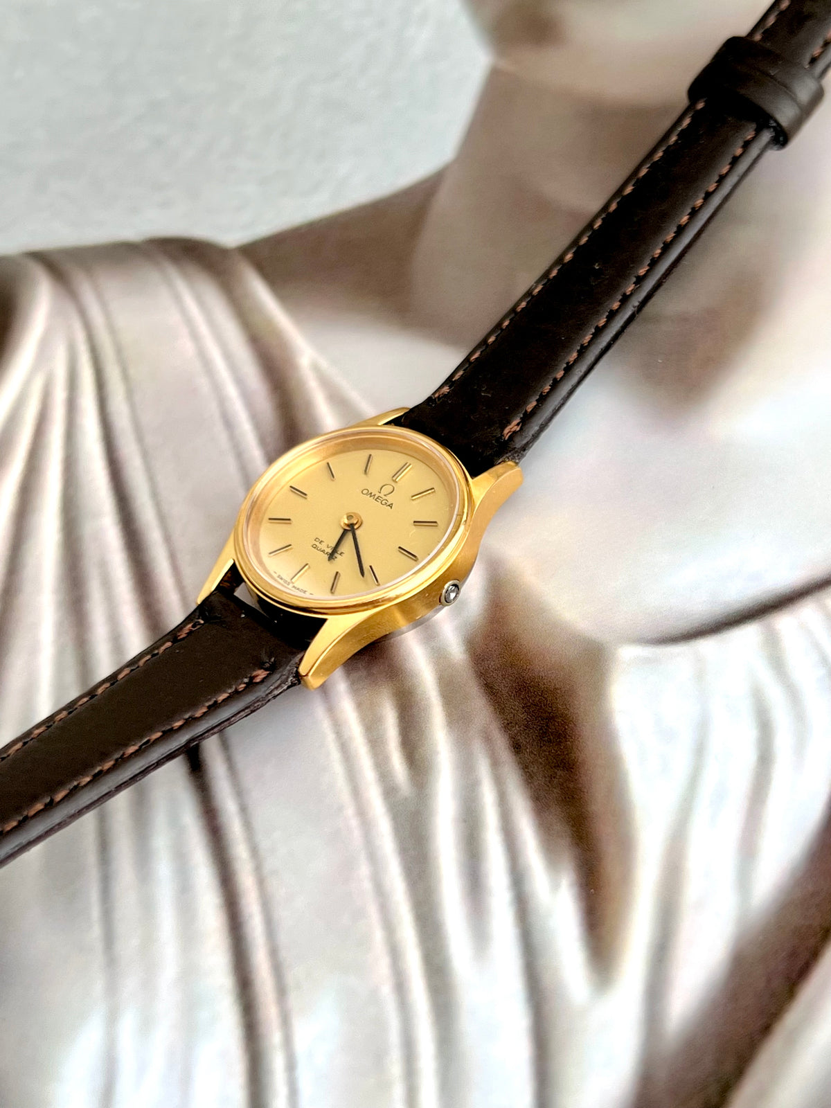 Omega De Ville gold-tone watch shown with its box.