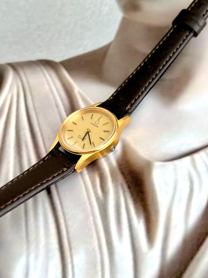 Omega De Ville gold-tone watch shown with its box.