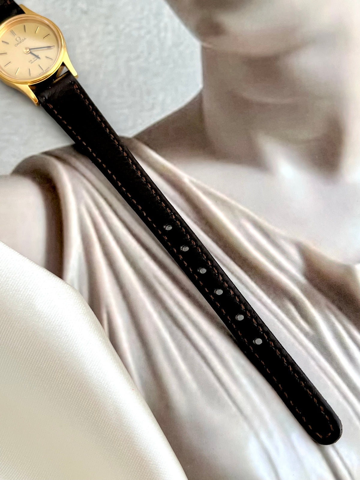 Side profile of the slim gold-tone case on the Omega De Ville watch.