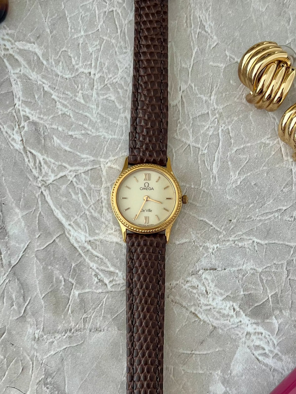 Omega De Ville Rope Bezel Brown Strap Watch: full front view on stone surface.