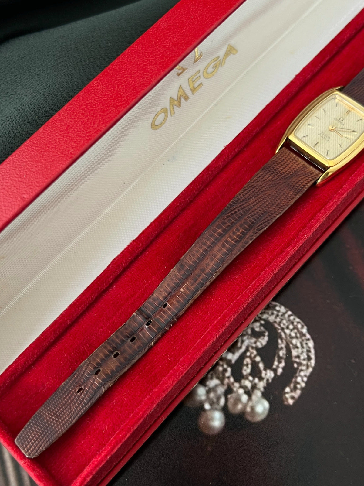 Close view of the brown lizard leather strap and gold tone tonneau case of the Omega De Ville watch.