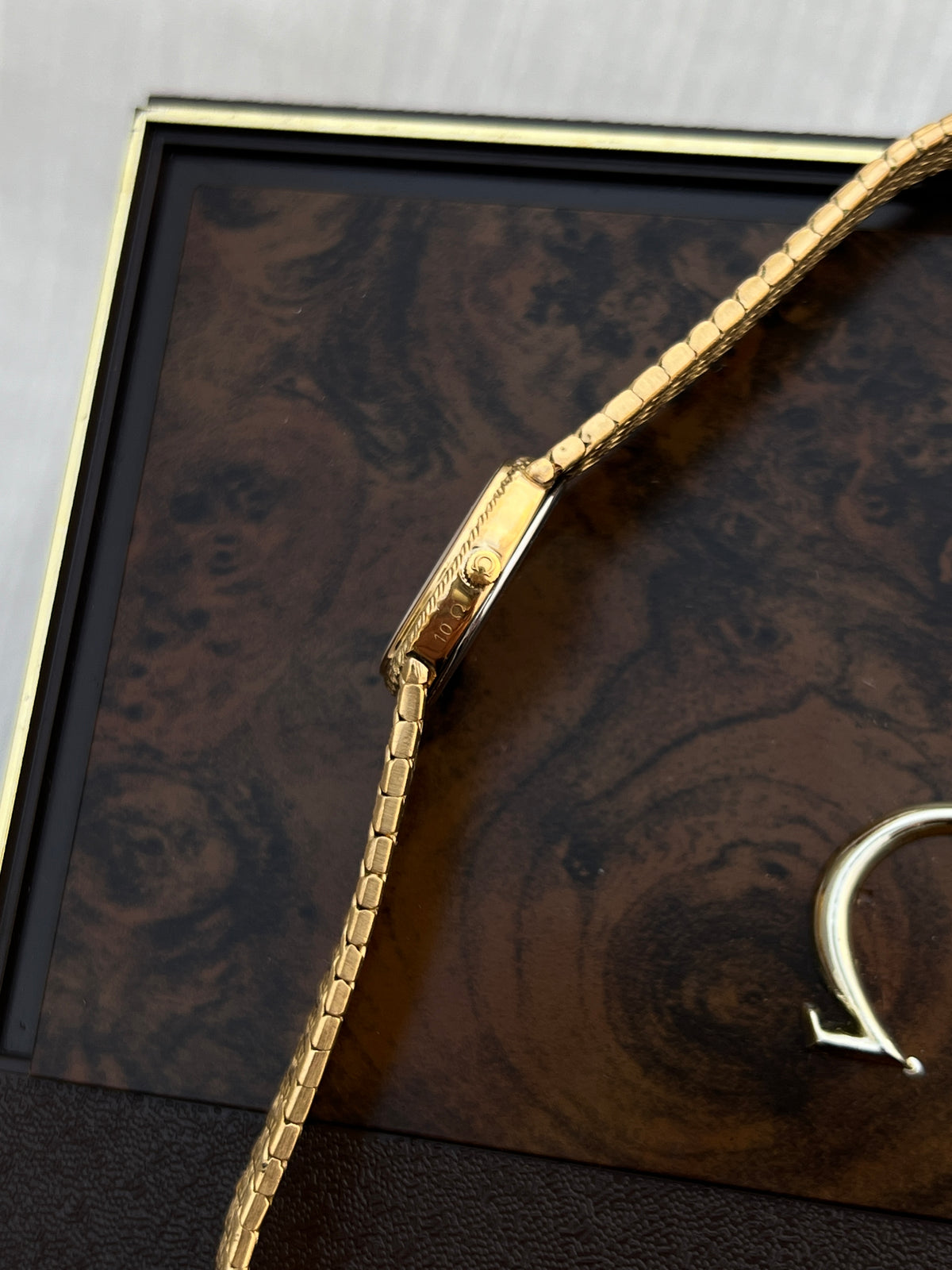 Angled view of the Omega De Ville oval case and integrated gold-tone bracelet.