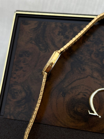 Angled view of the Omega De Ville oval case and integrated gold-tone bracelet.