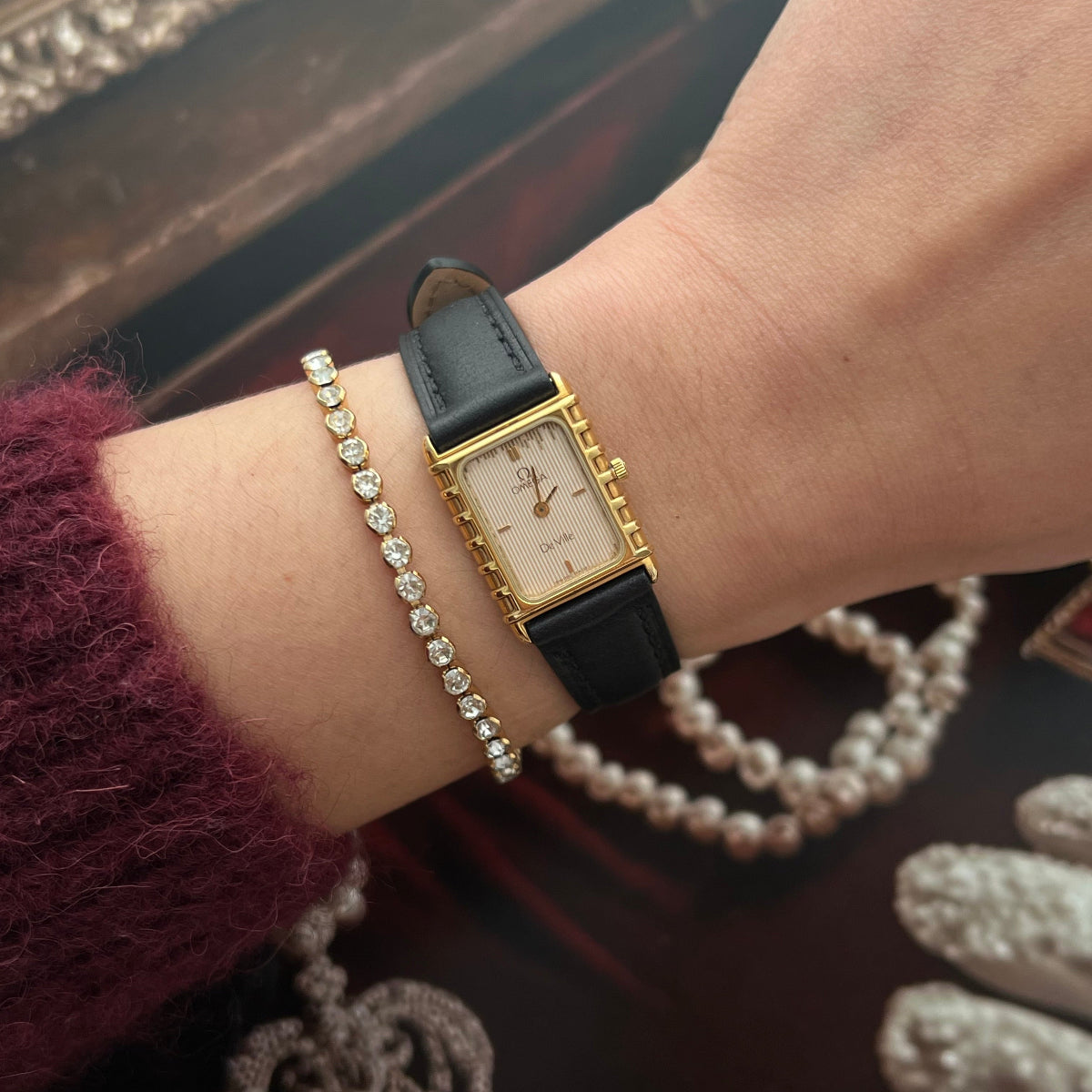Omega De Ville gold women’s watch with fluted champagne dial, stepped rectangular case and black leather strap