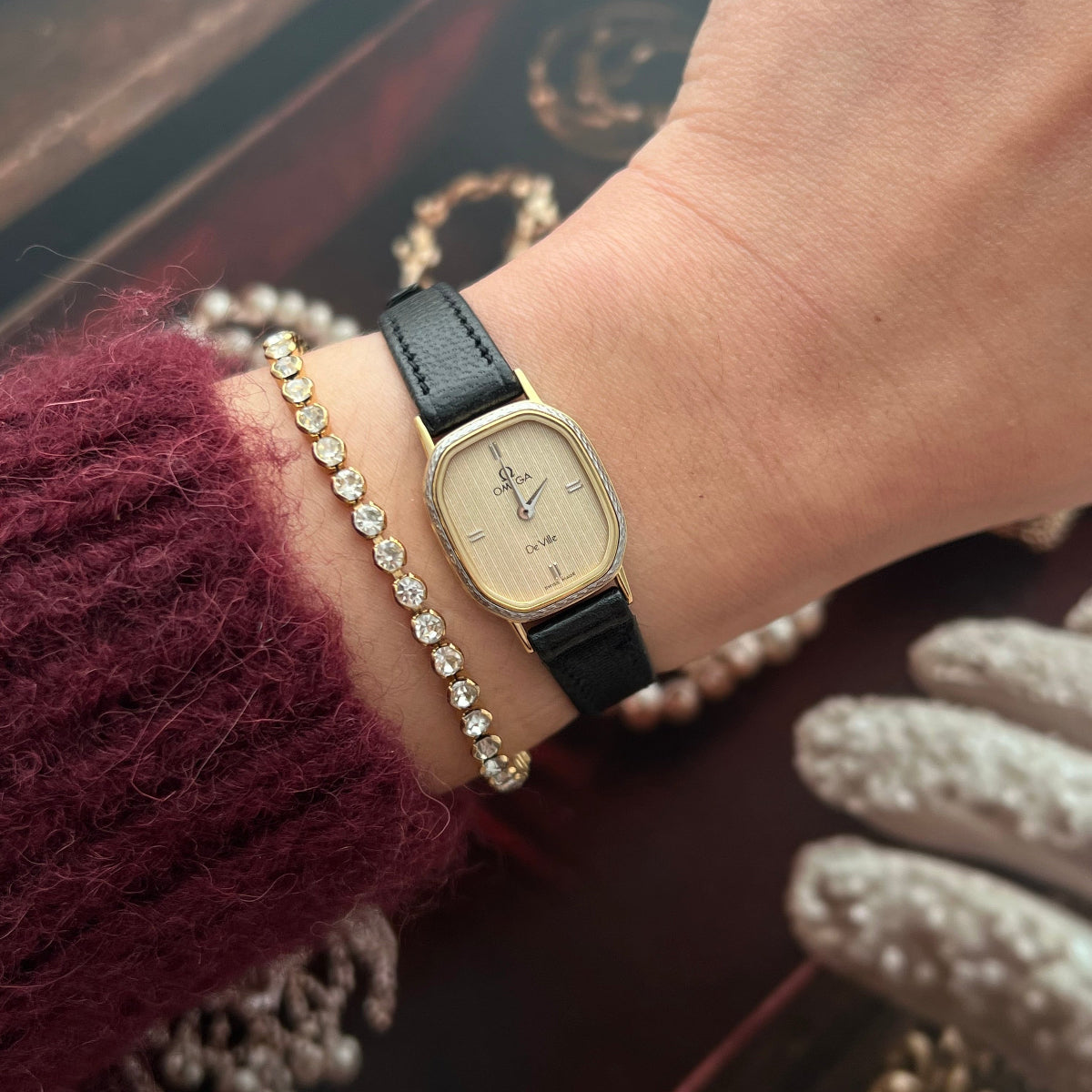 Omega De Ville gold women’s watch with textured champagne dial, Roman numerals and black leather strap