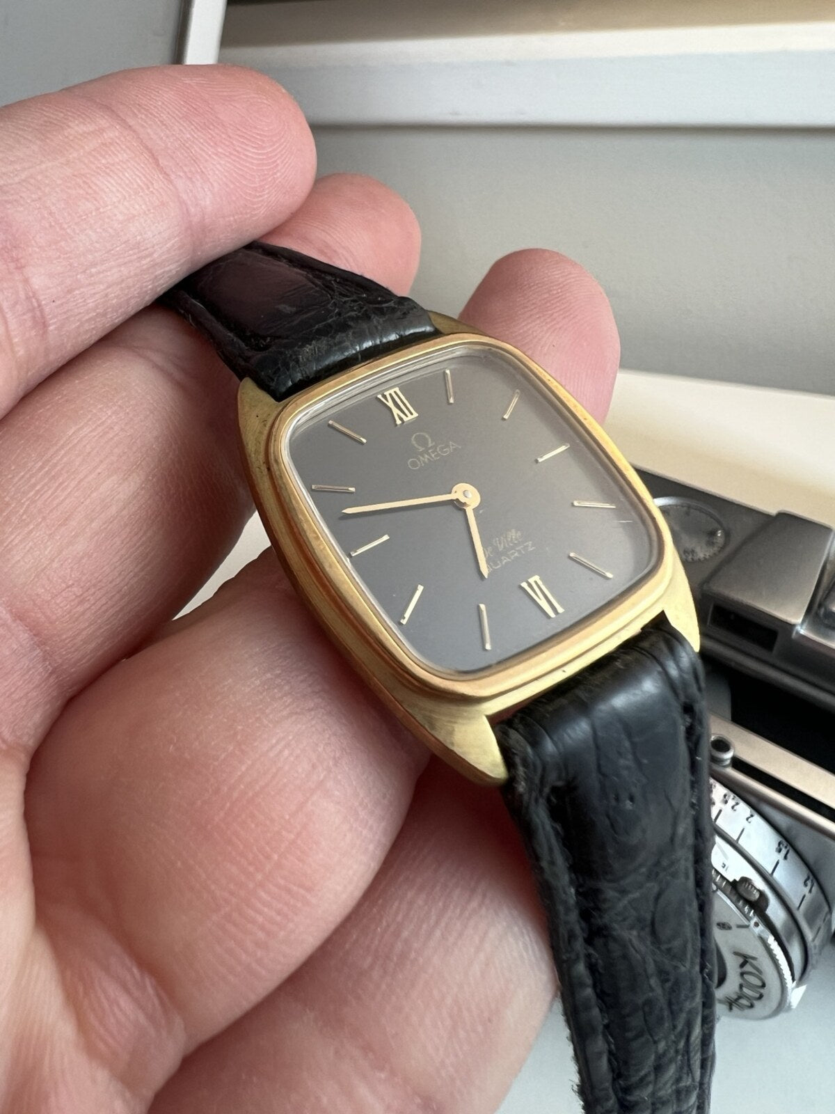 Close view of the Omega De Ville ash grey dial with gold baton markers and Roman numerals at twelve and six.