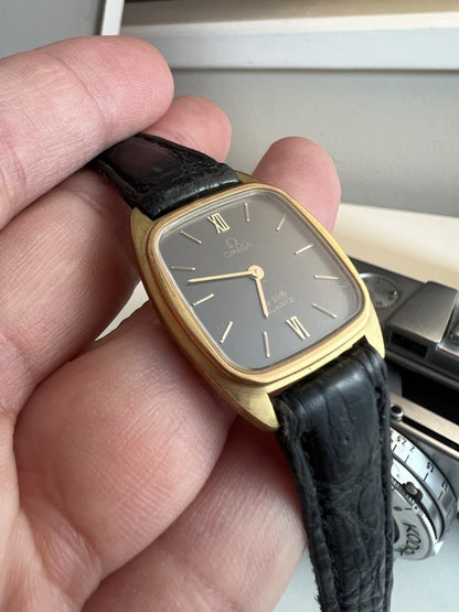 Close view of the Omega De Ville ash grey dial with gold baton markers and Roman numerals at twelve and six.