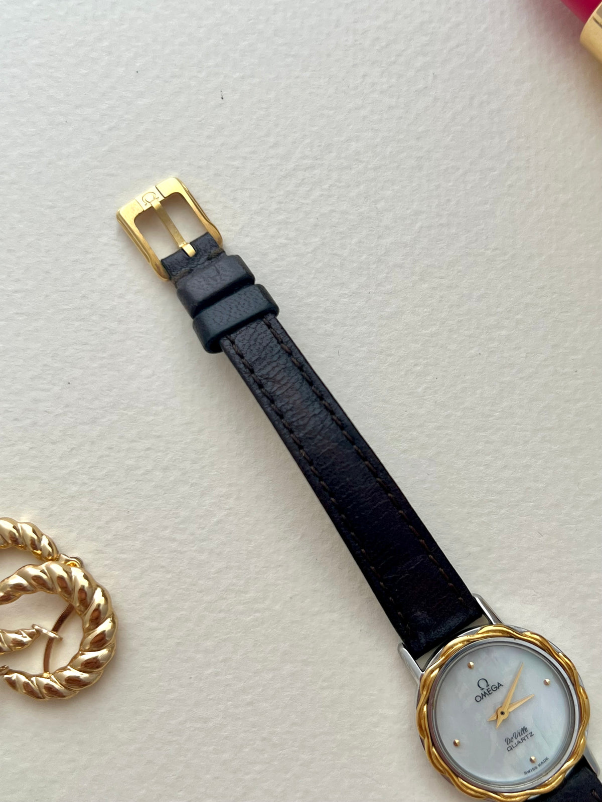 Side angle of the Omega De Ville case showing its sculpted gold laurel bezel.