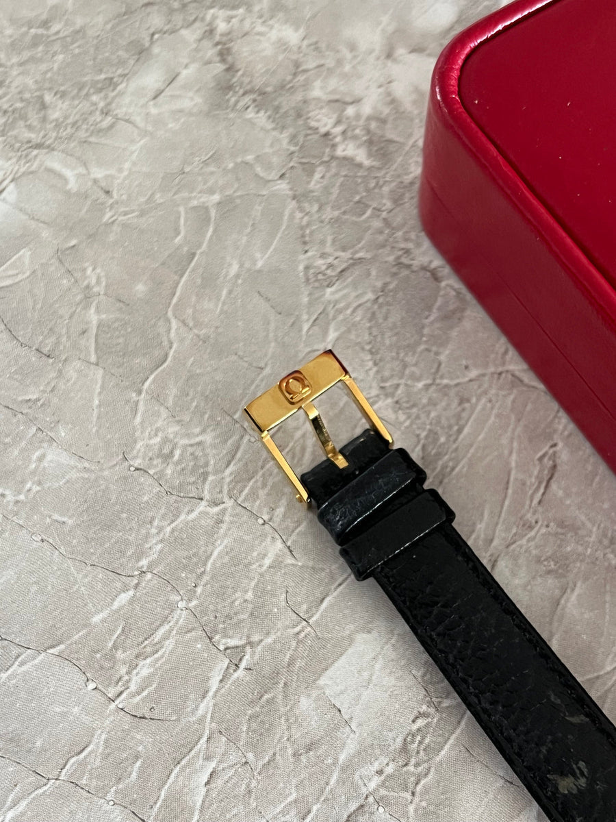 Detail view of the Omega-signed gold-tone pin buckle and black leather watch strap