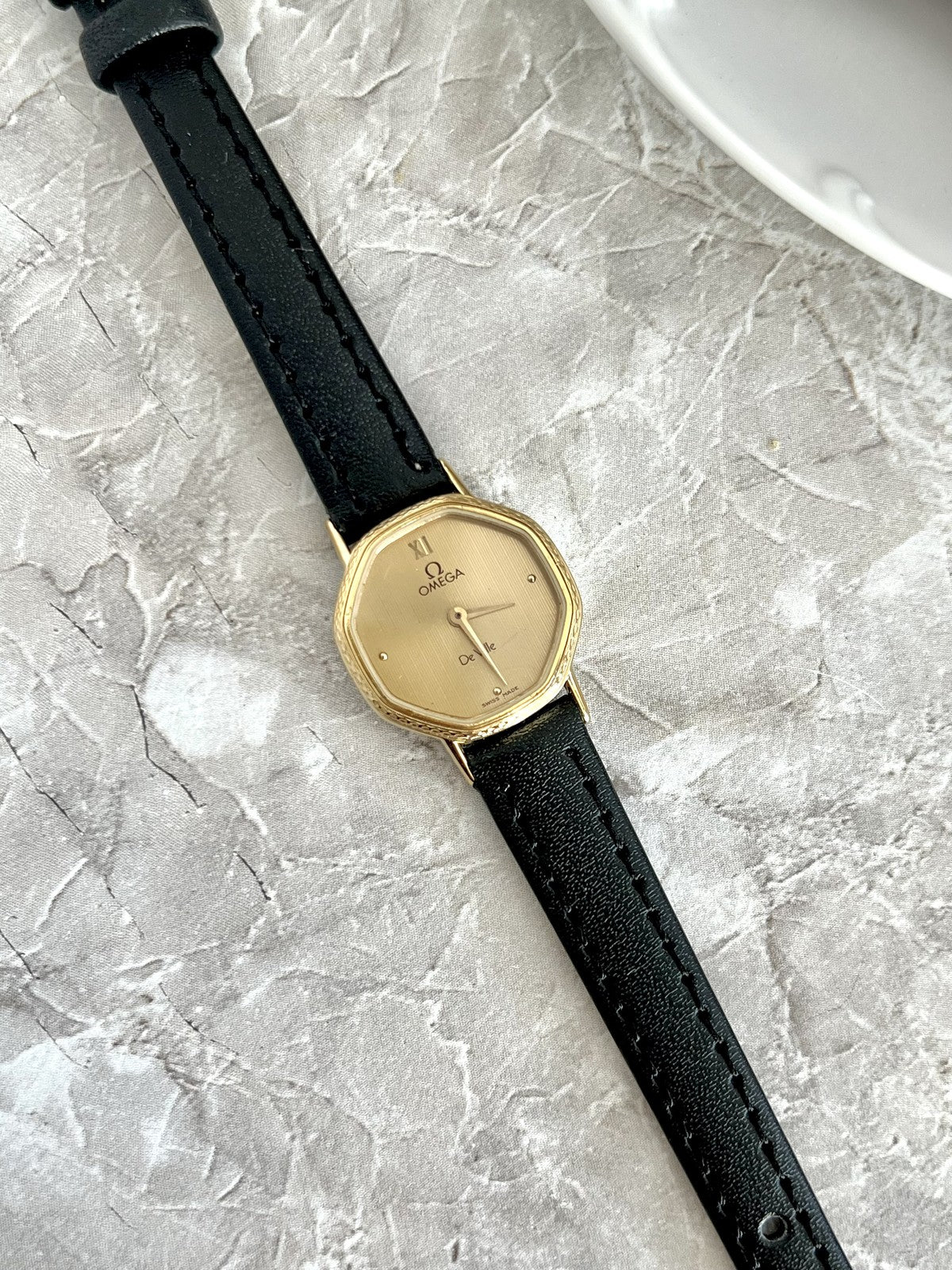 Omega De Ville calibre 1387 quartz watch with champagne dial and black strap, angled detail — ref. 591.0257