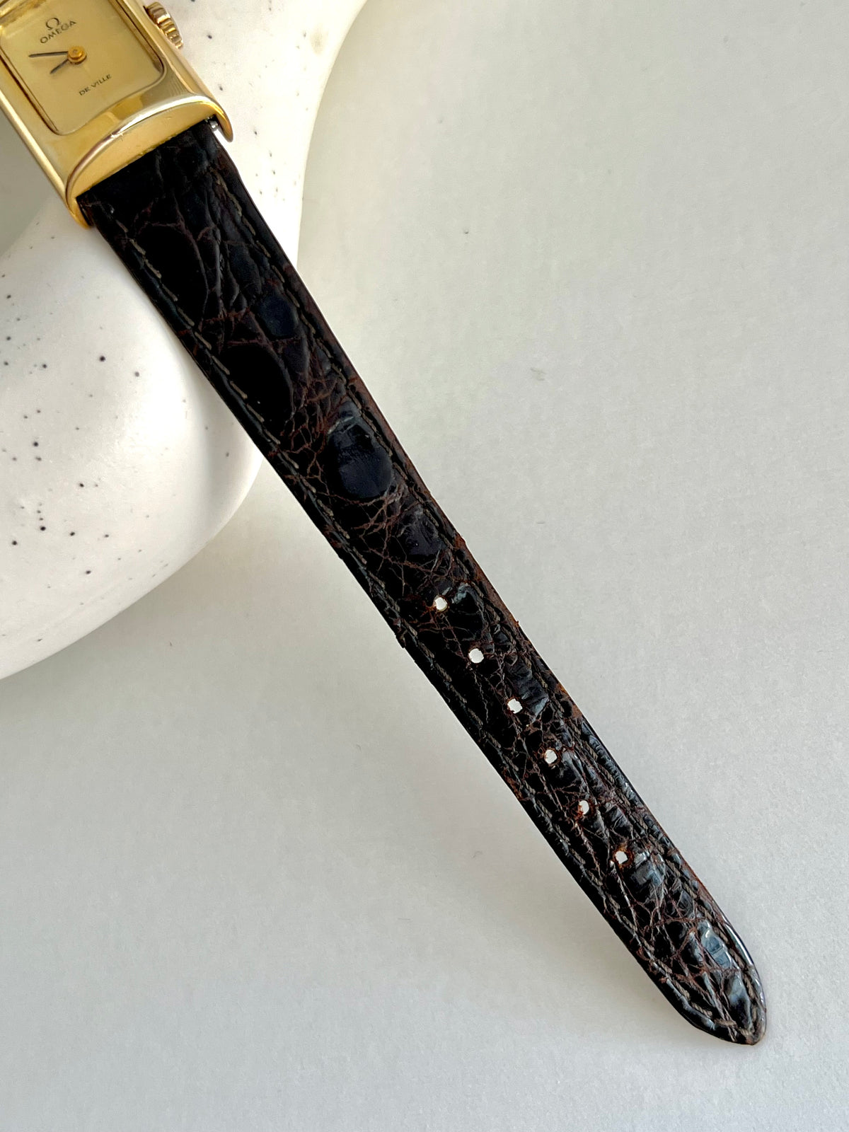 Angled view of the Omega De Ville rectangular gold-tone watch.