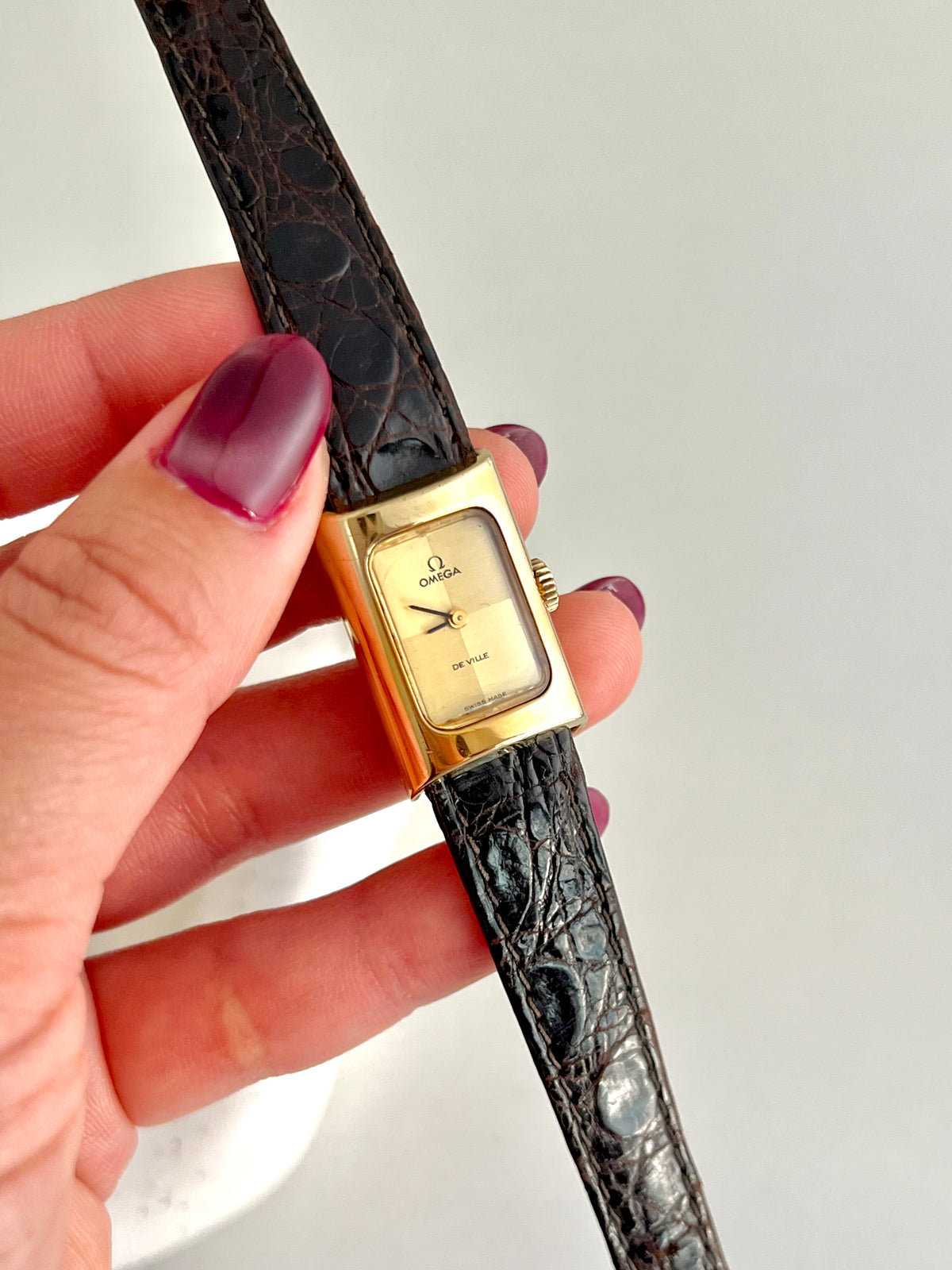 Front view of the Omega De Ville gold rectangular watch with chequered dial.