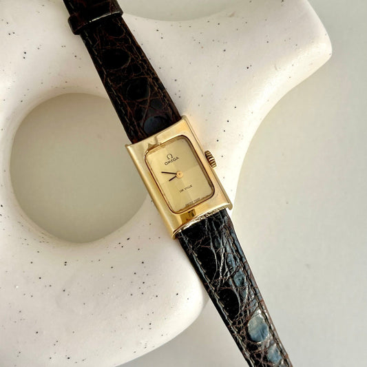 Omega De Ville gold mechanical watch with rectangular case and original croc-style strap.