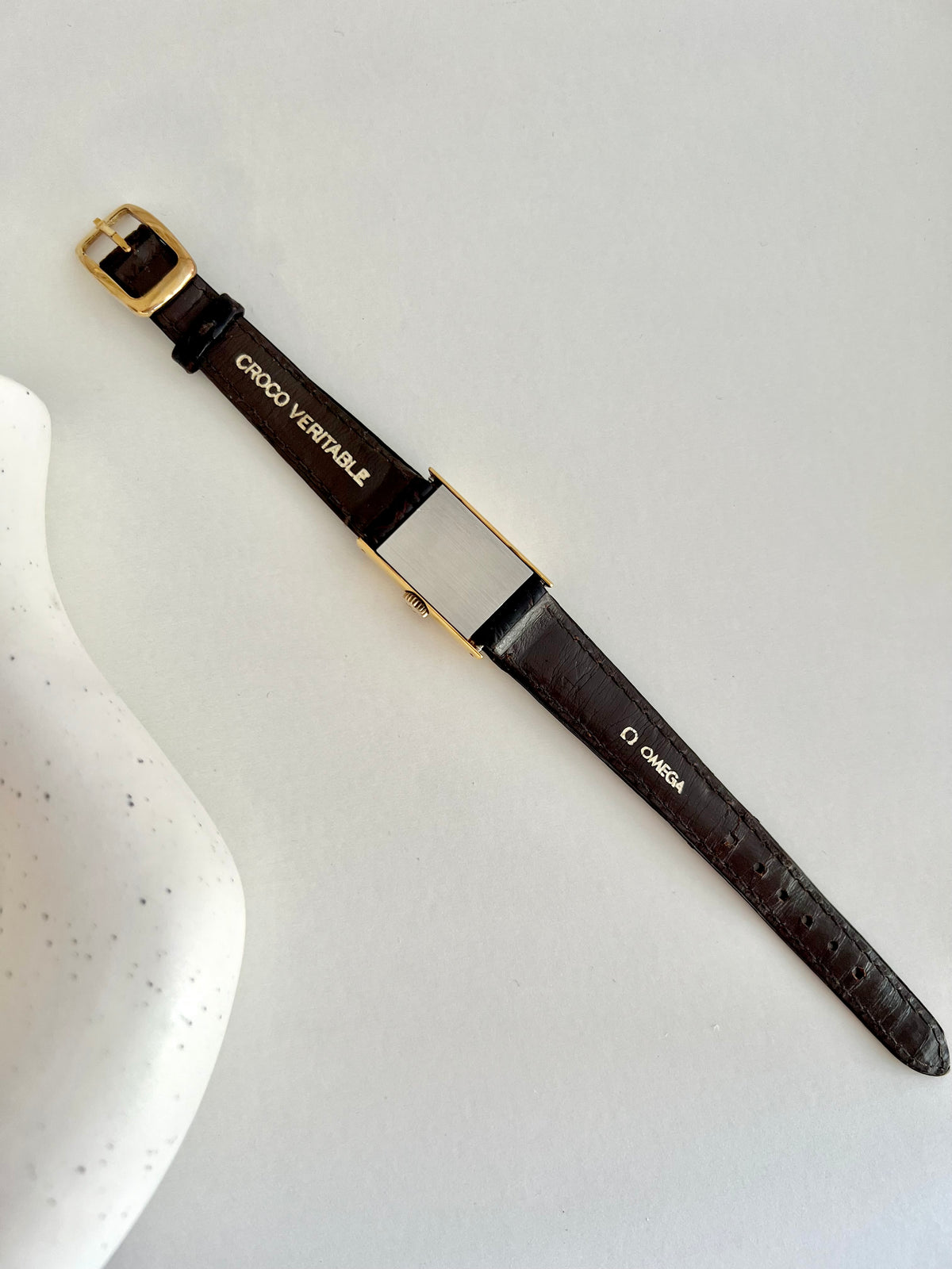Detail of the original Omega croc-style strap and signed buckle.