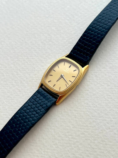 Omega De Ville gold-tone rope-bezel watch shown on a wrist.
