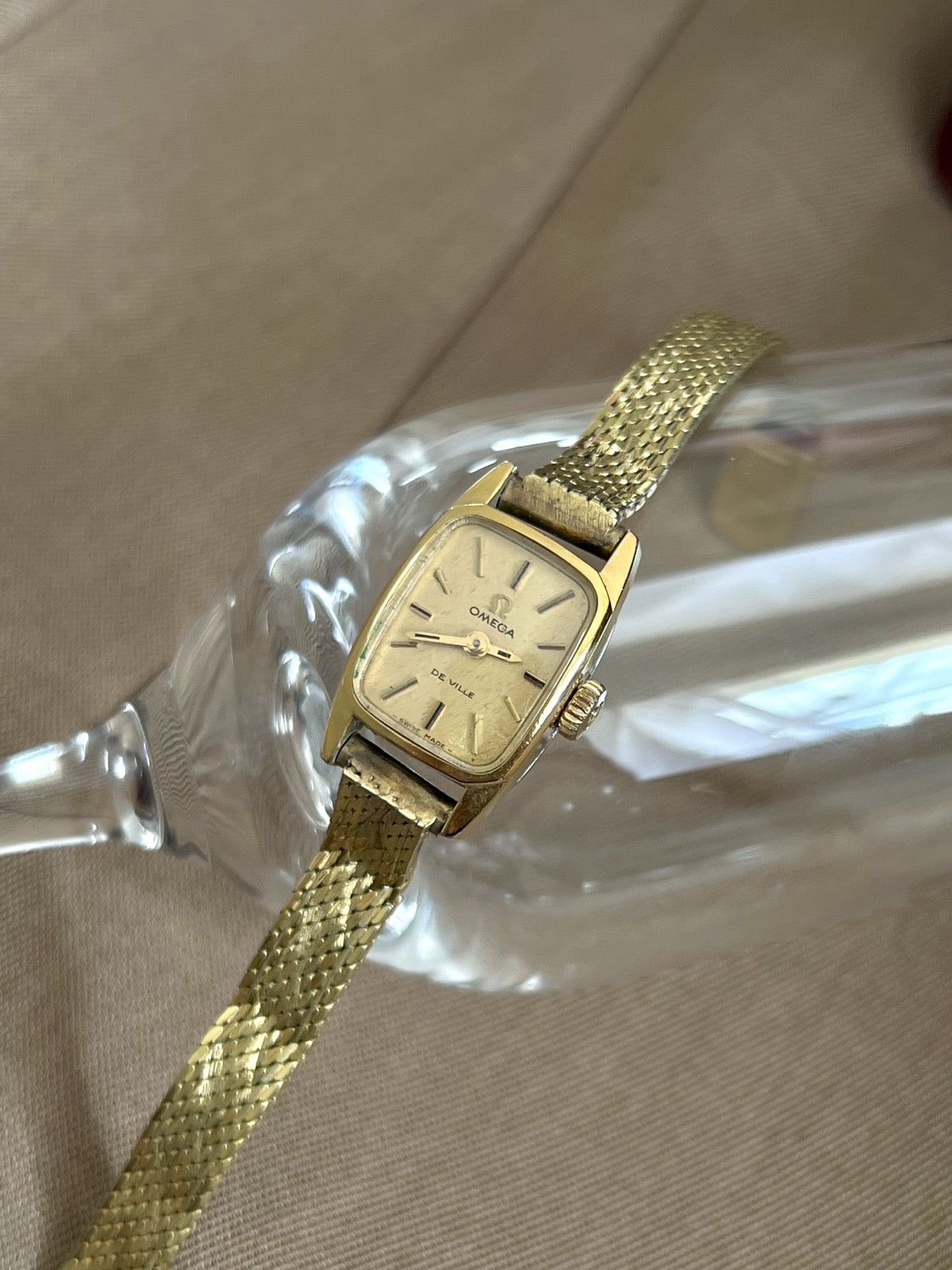 Close view of the gold snowflake textured dial, baton markers and two hands on the Omega De Ville women’s watch