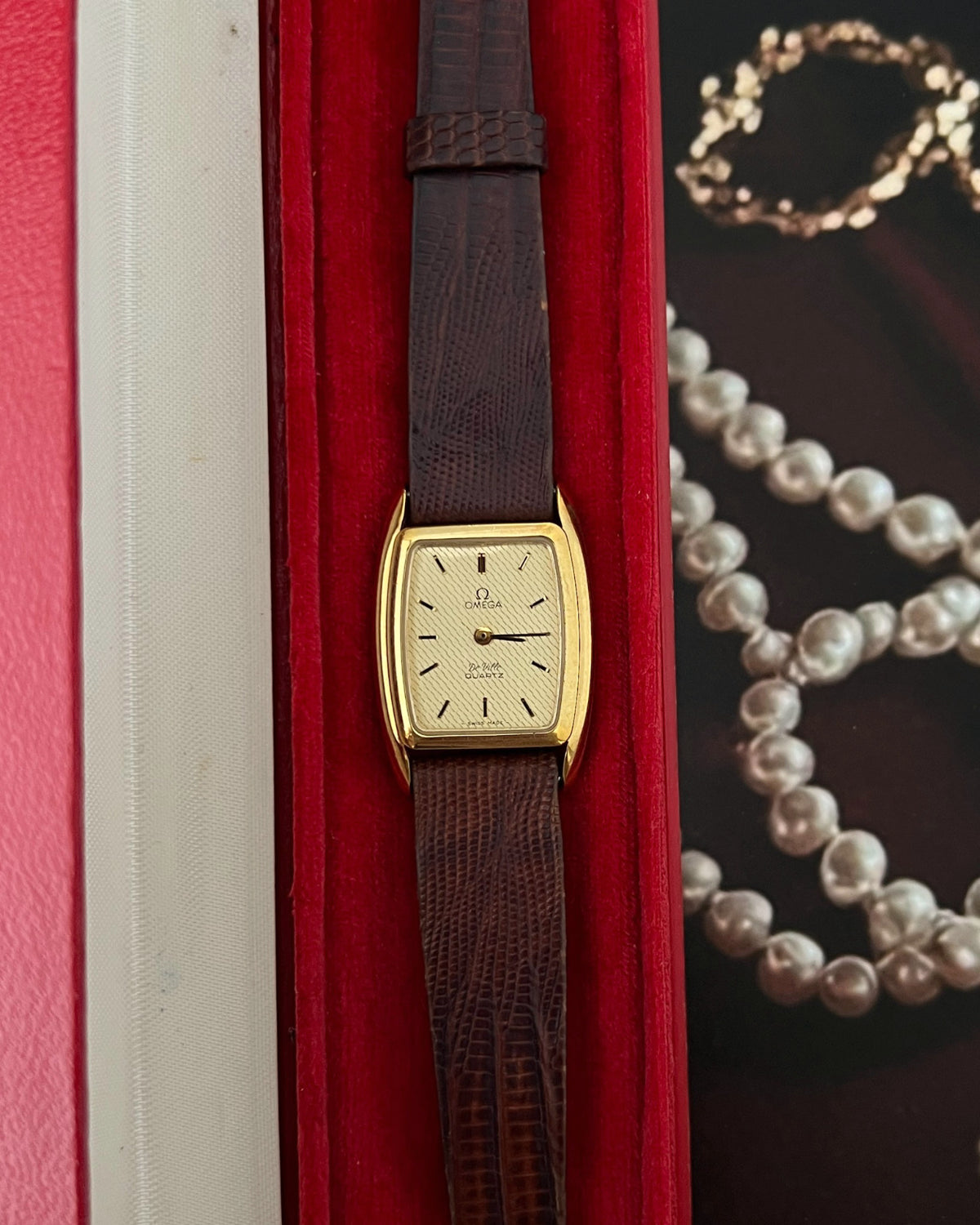 Upright front view of the Omega De Ville wavy champagne dial, slender hour markers and gold tone tonneau case.