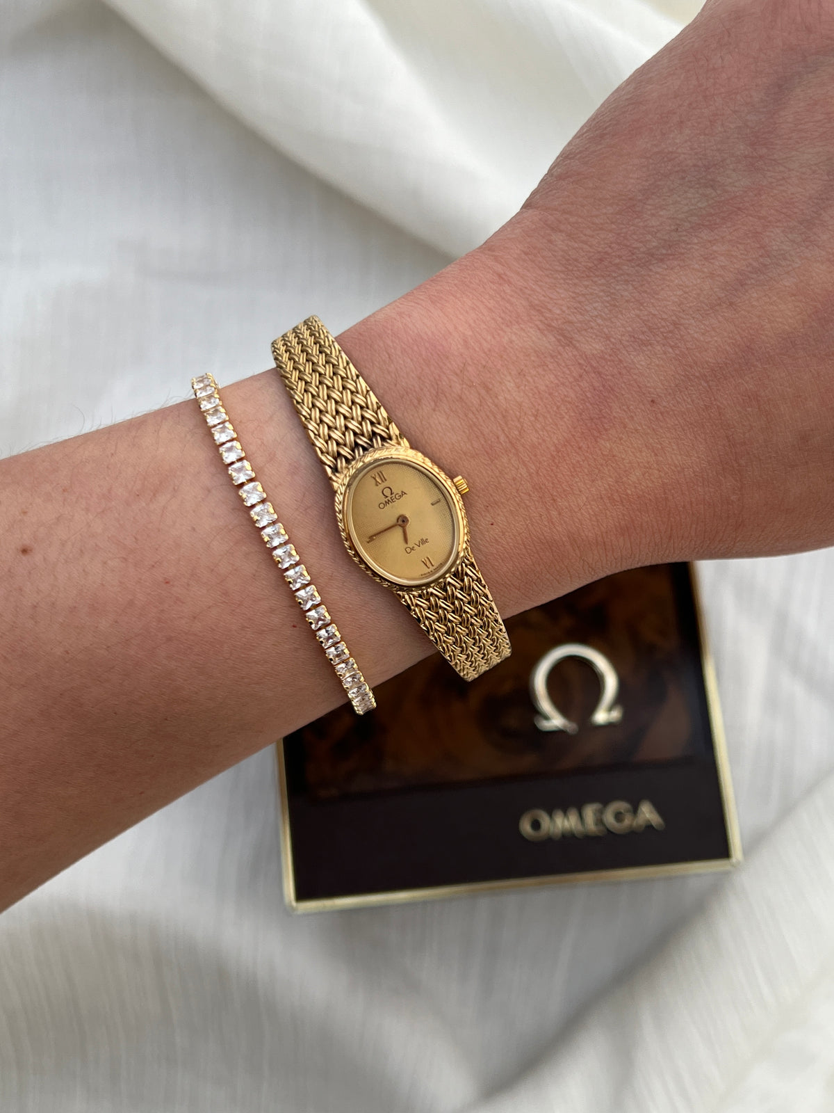 Side profile of the Omega De Ville case with a detail of its woven wheat-pattern bracelet.