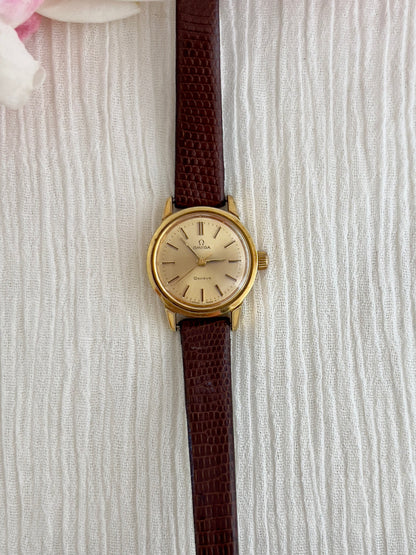 Side profile of the gold-tone case on the Omega Geneve watch.