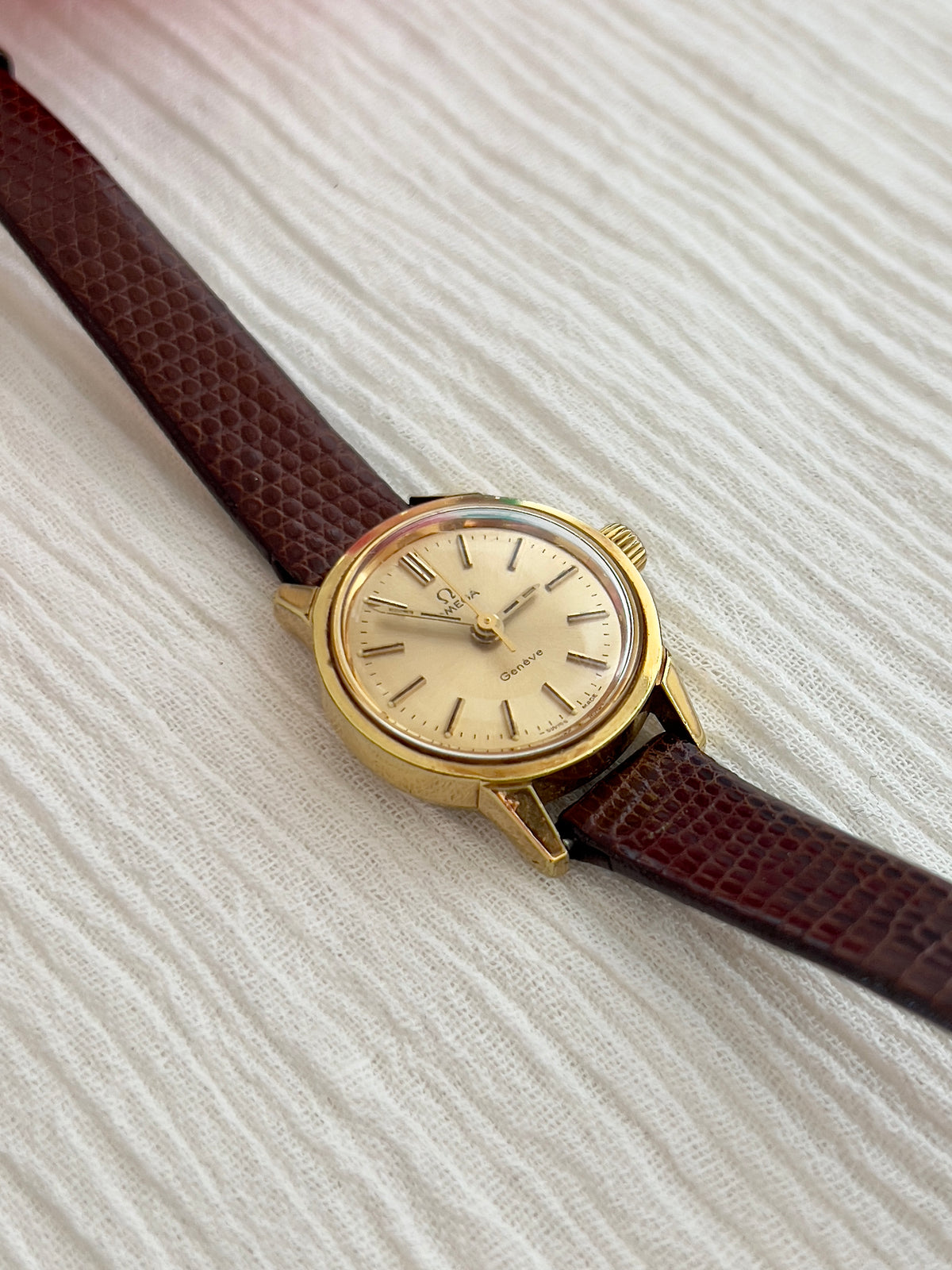 Brown leather strap detail on the Omega Geneve watch.