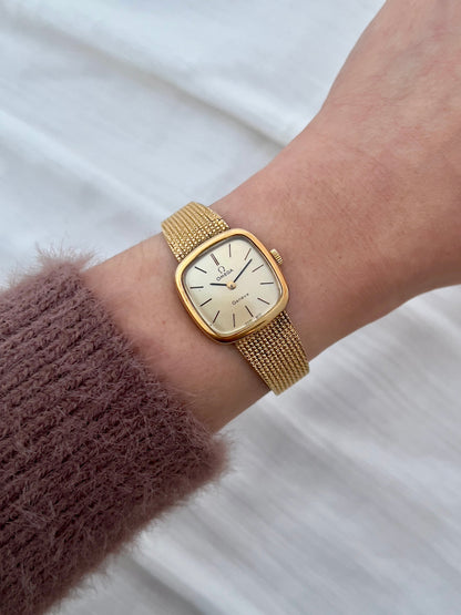 Wrist view of the Omega Geneve gold mesh bracelet watch.