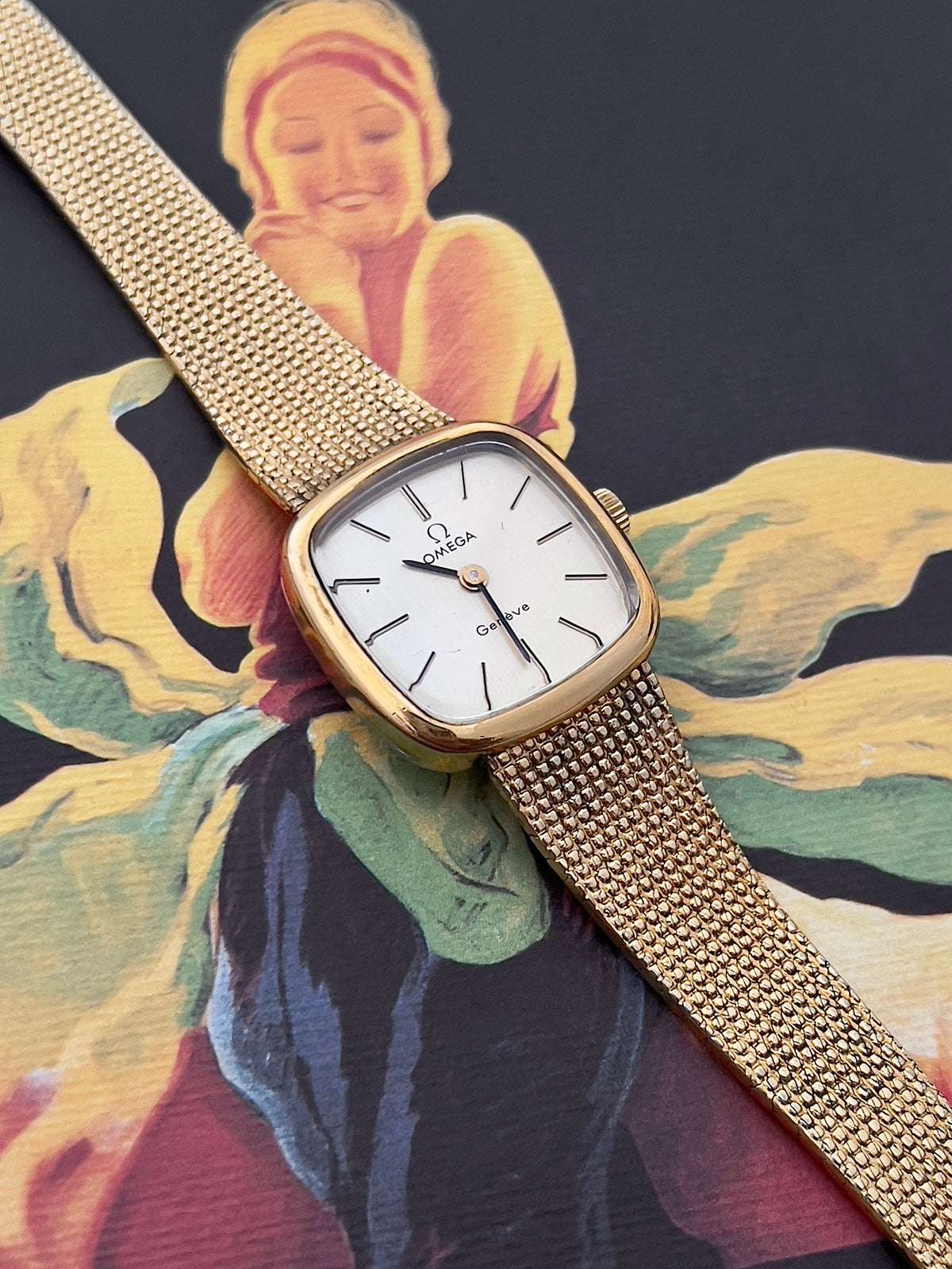 Front view of the Omega Geneve with silver dial and rounded-square gold-tone case.