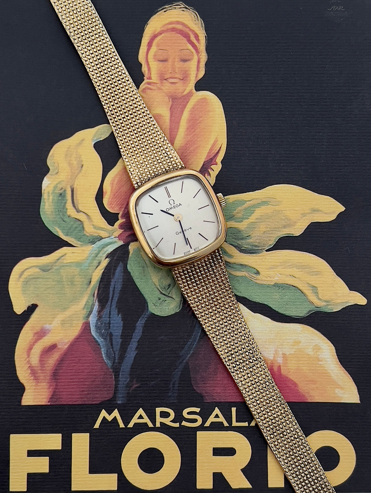 Angled view of the Omega Geneve gold-tone case and integrated mesh bracelet.