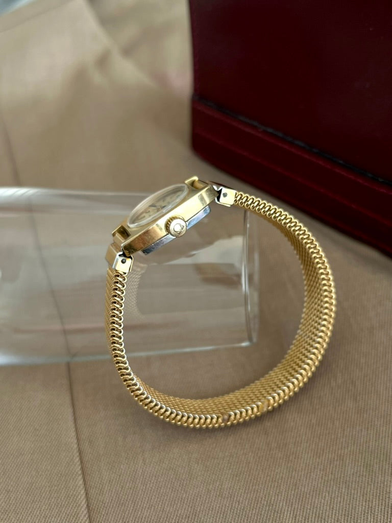 Side view of the Omega Geneve women’s watch showing its Omega signed crown, slim case and gold mesh bracelet