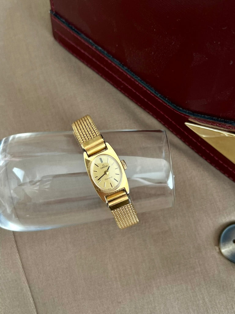 Omega Geneve oval dial women’s watch displayed on glass beside a red jewellery box